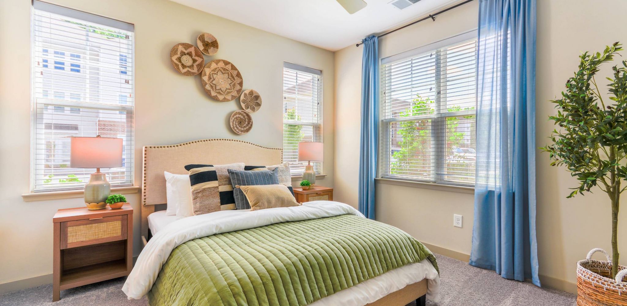 Hawthorne at St. Marks well-lit bedroom with a green bedspread and dual windows.