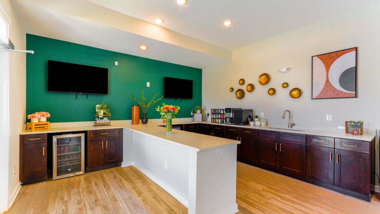The communal kitchen area at Hawthorne at St. Marks, showcasing a sleek design with dark cabinets and green accent wall.